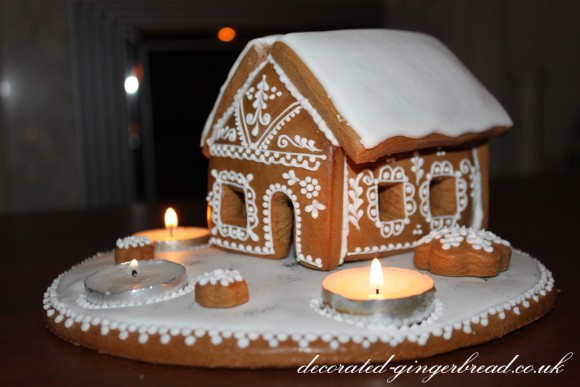 Decorated gingerbread house with 3 candles